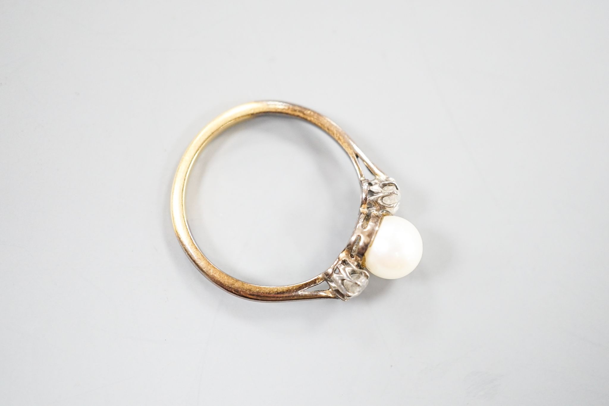 An early 20th century 18ct, single cultured pearl and two stone diamond set ring, size N, gross weight 2.5 grams.